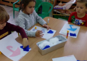 Dzieci podczas pracy plastycznej przy stole.